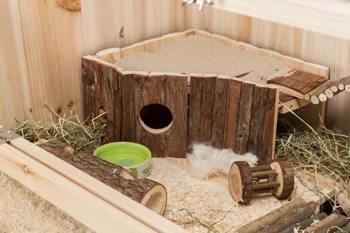 Holzgehege mit Häuschen, Heu, Trinkschale und hölzernem Spielzeug auf Holzboden.