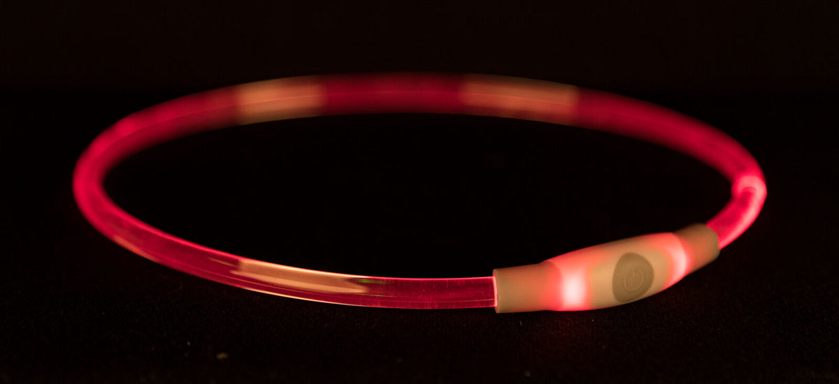 Leuchtender, pinkfarbener Ring auf schwarzem Hintergrund, mit einem kleinen weißen Schalter.