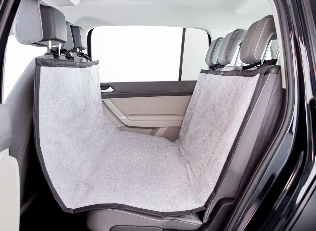 Rücksitz eines Autos mit grauem Schonbezug, der über die Sitze gespannt ist und Kopfstützen umschließt.