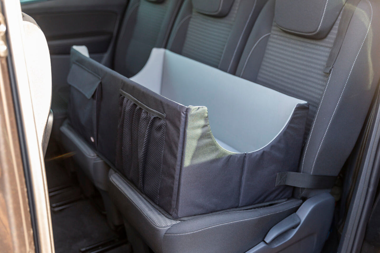 Schwarzer Autohundesitz auf einer Rückbank mit Taschen und Gurtbefestigung.