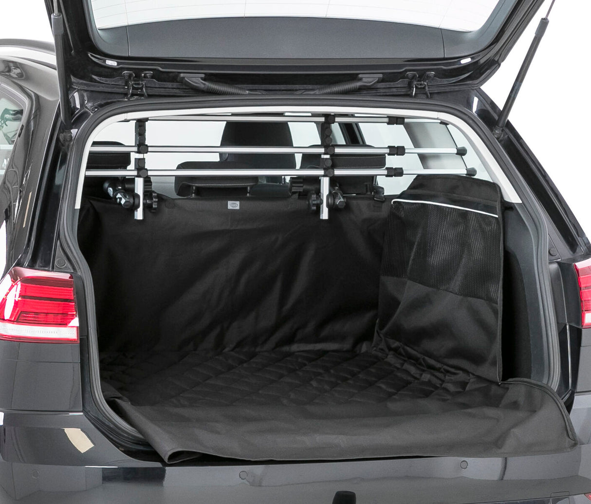 Offener Kofferraum eines Autos mit schwarzer Schutzhülle, Metallgitter und Tasche an der Rückseite.