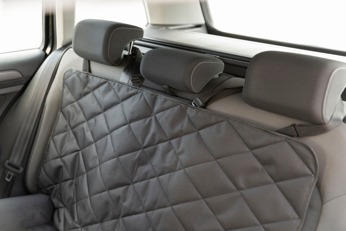Schwarze, gesteppte Autoschondecke auf einer Rückbank mit Kopfstützen, gut erkennbar in einem Fahrzeug.