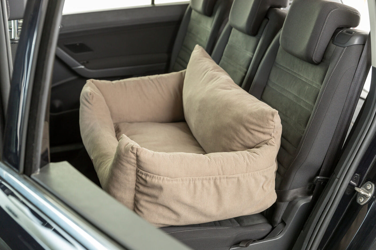 Beiges Hundebett auf dem Rücksitz eines Autos, umgeben von schwarzen Autositzen.