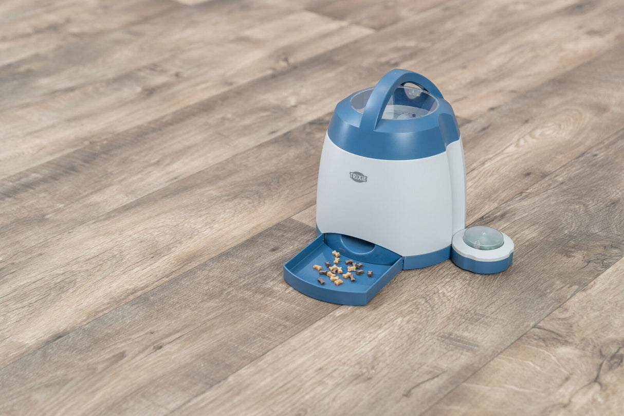 Automatischer Futterspender von TRIXIE auf Holzboden mit blauen Akzenten und geöffneter Klappe.