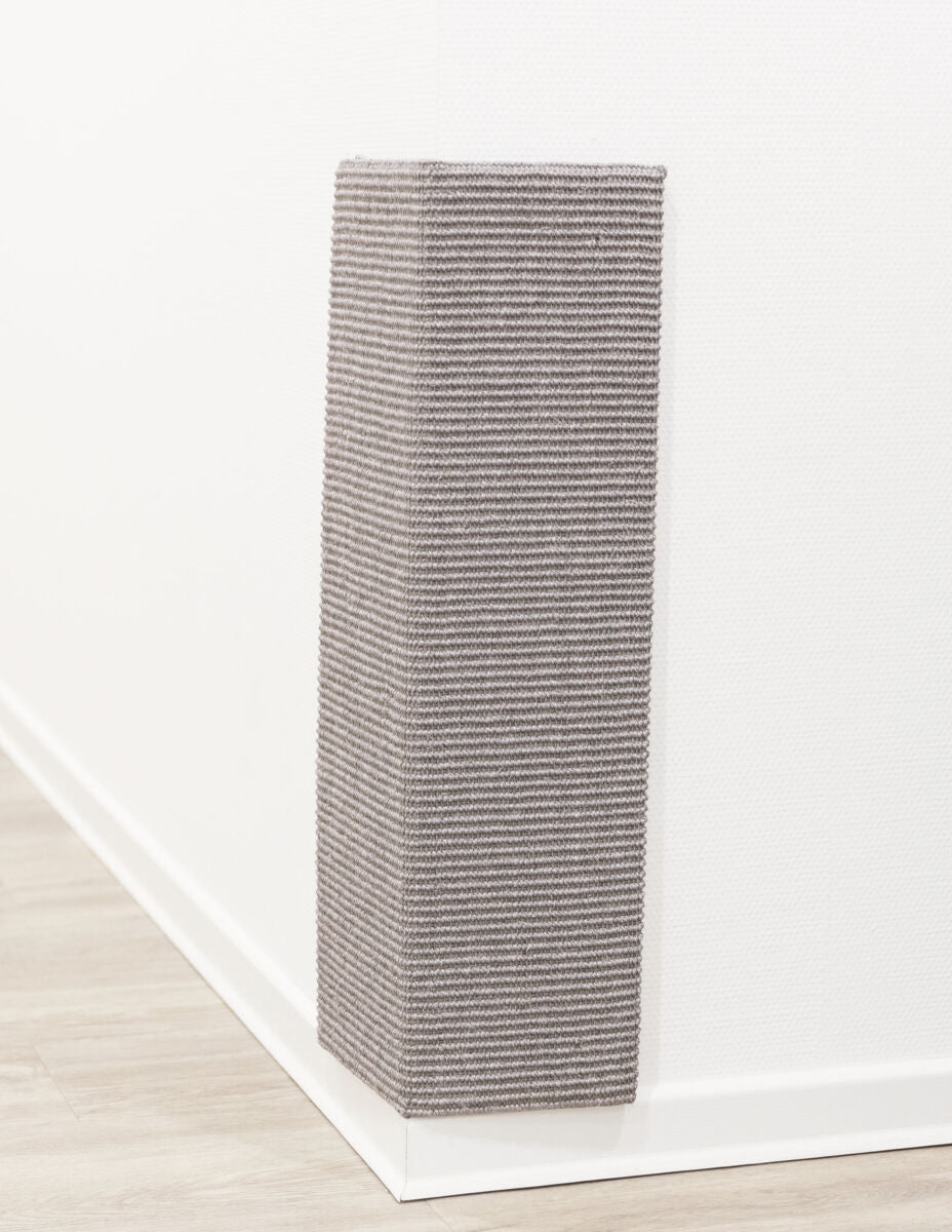 Eckige Wandverkleidung aus grauem, geripptem Material, montiert an einer weißen Wand mit Holzfußboden.