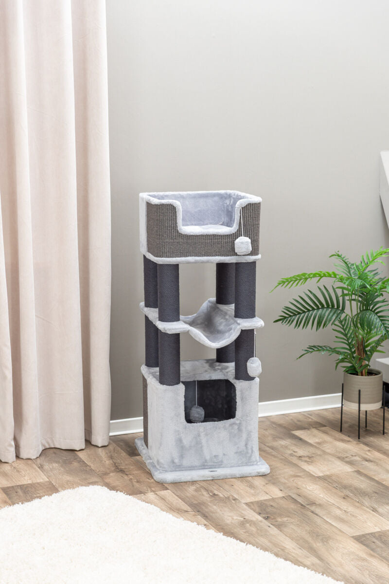 Kratzbaum mit mehreren Ebenen, grauen und schwarzen Flächen, Quasten, auf Holzboden vor beiger Wand und Vorhang.