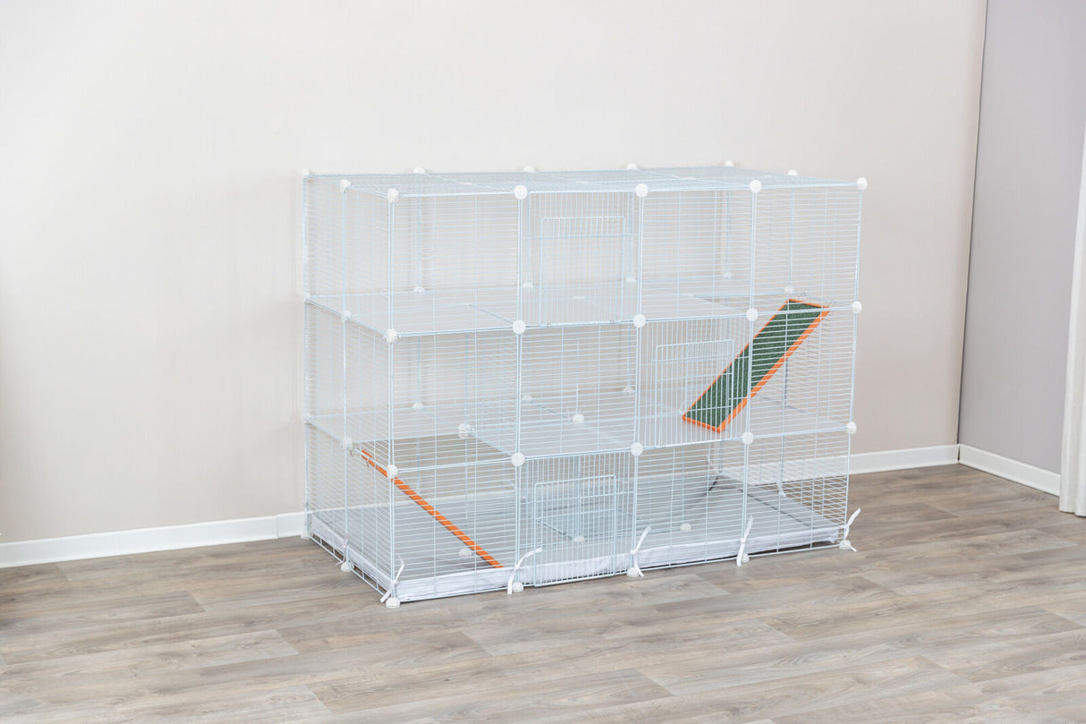 Weiße, mehrstöckige Gitterkonstruktion mit Rampen auf Holzfußboden vor einer hellen Wand.