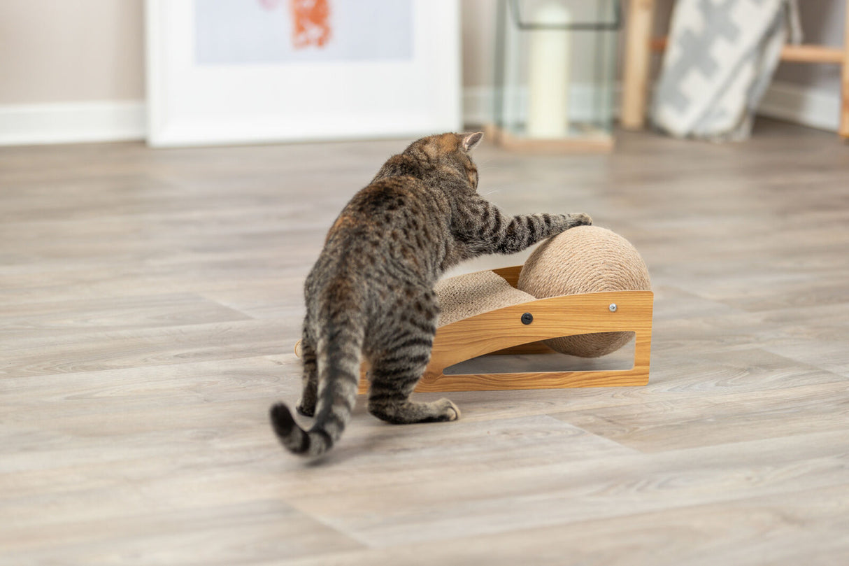 Eine getigerte Katze spielt auf einem Holzboden mit einem Kratzspielzeug aus Holz und Sisal.