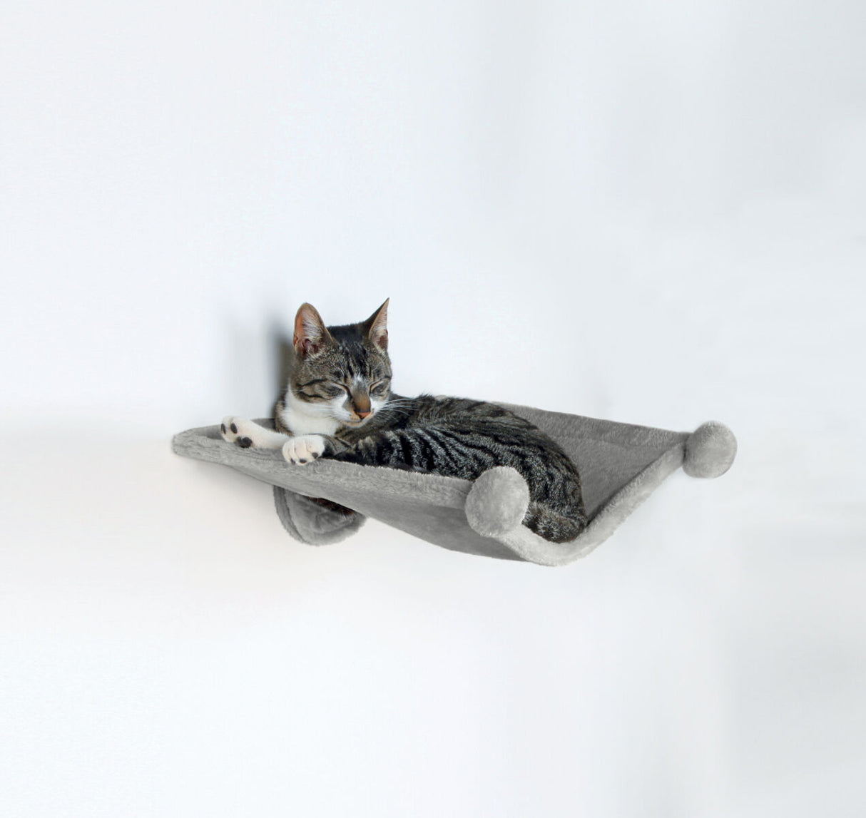 Eine getigerte Katze liegt auf einer an der Wand befestigten, grauen Hängematte und scheint zu ruhen.