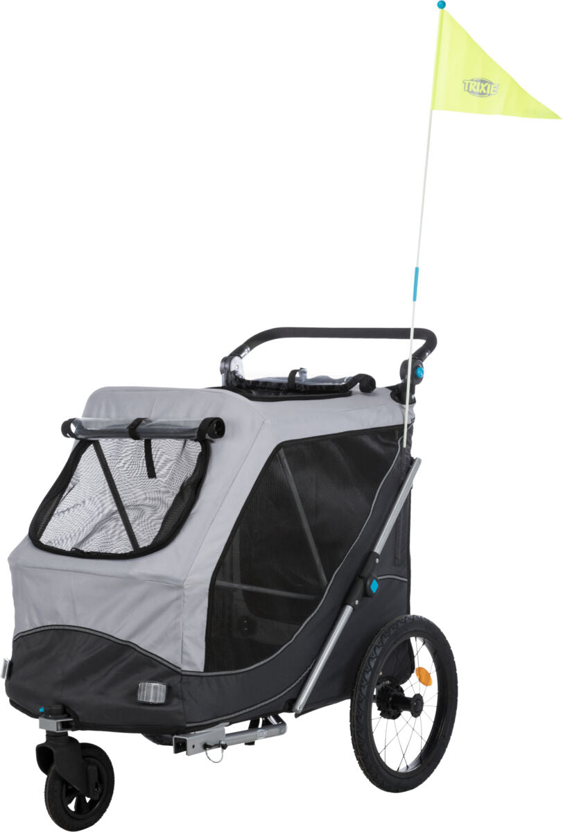 Grau-schwarzer Fahrradanhänger mit drei Rädern, Netzfenstern und gelber Fahne, aufrecht stehend.