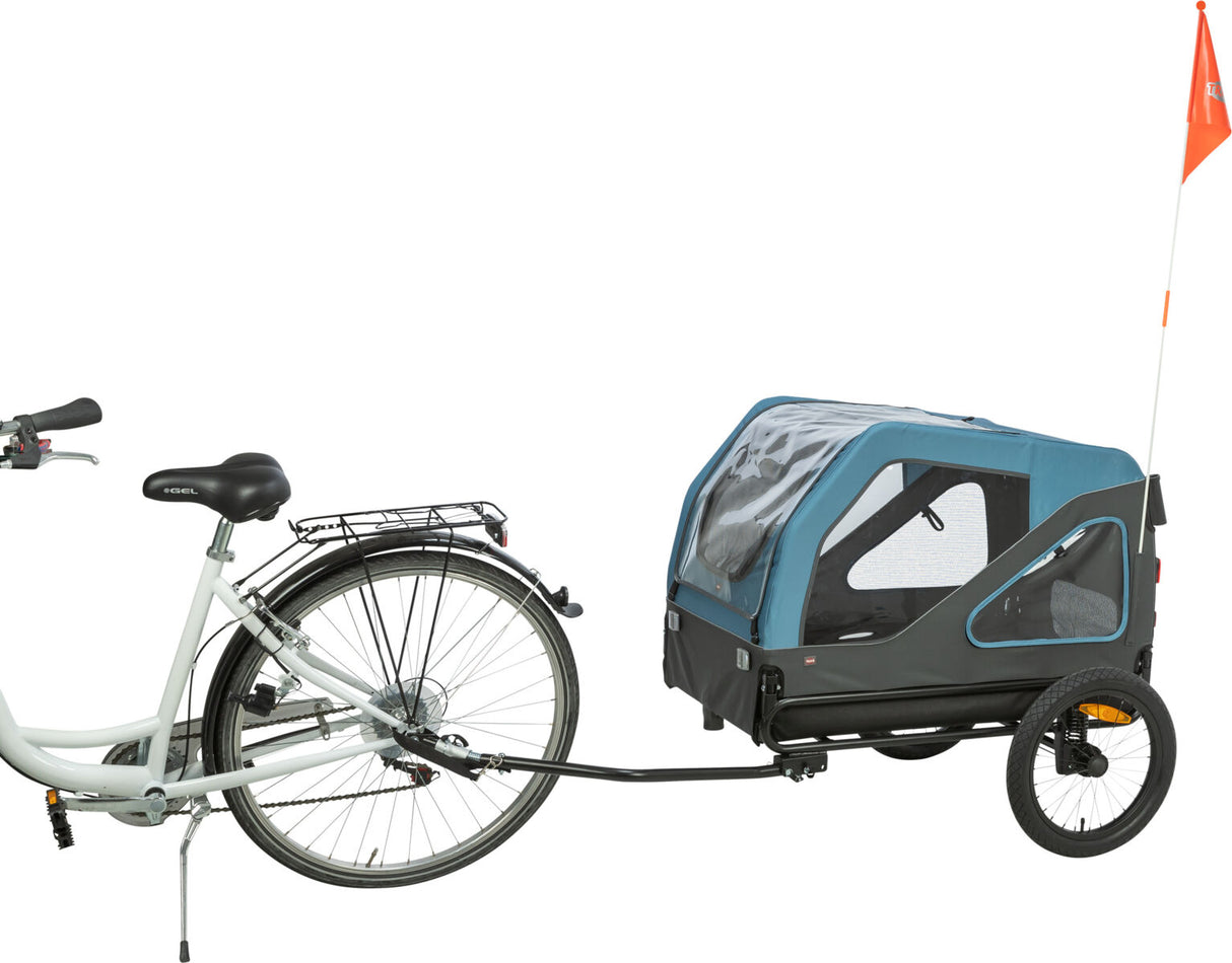 Blauer Fahrradanhänger mit schwarzen Details, befestigt an einem weißen Fahrrad, orangefarbene Fahne am Anhänger.