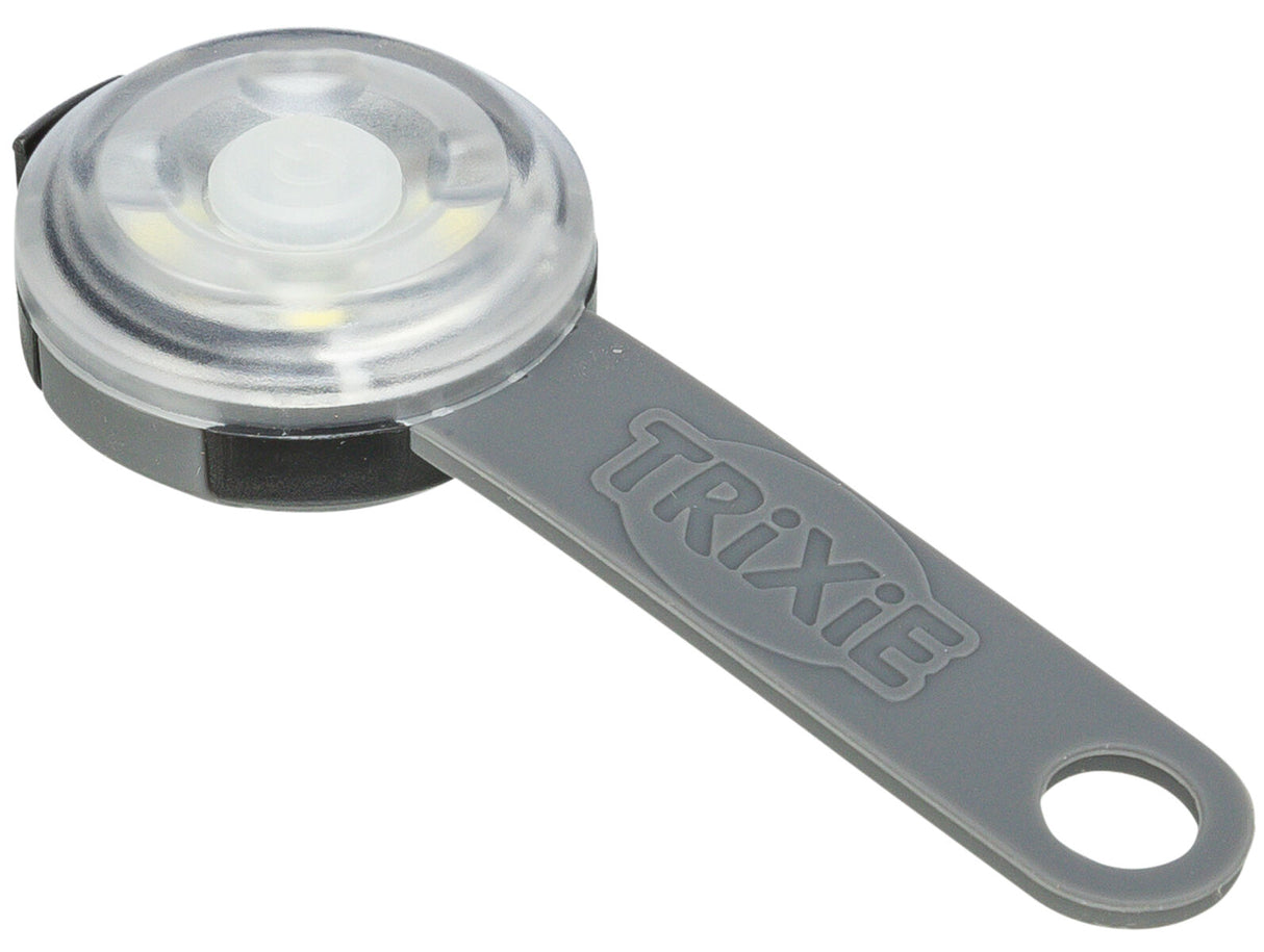 Graues Kunststoff-Licht mit runder, transparenter Abdeckung und Schlaufe, Markenname "Trixie" erkennbar.