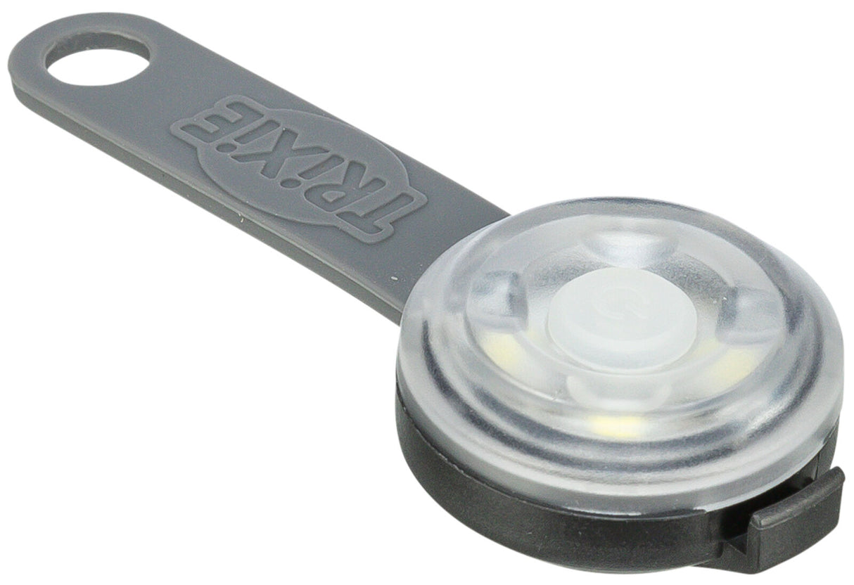 Rundes, graues Leuchtartikel mit Klarsicht-Abdeckung und Schlaufe, Markenname sichtbar.