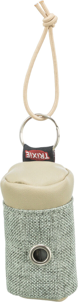 Beigefarbener Tasche mit Kordel, Metallring und kleiner Öffnung auf der Vorderseite, Text "TRIXIE" sichtbar.