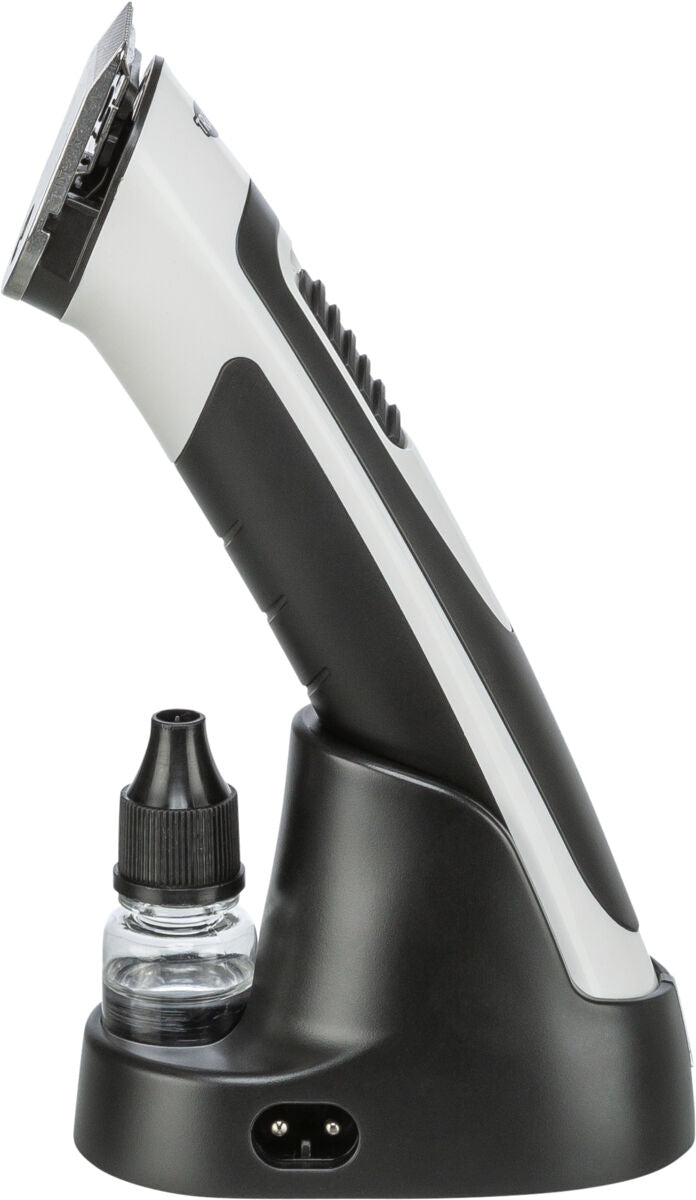 Elektrischer Haarschneider in Schwarz und Weiß mit Ladestation und kleinem Ölfläschchen daneben.