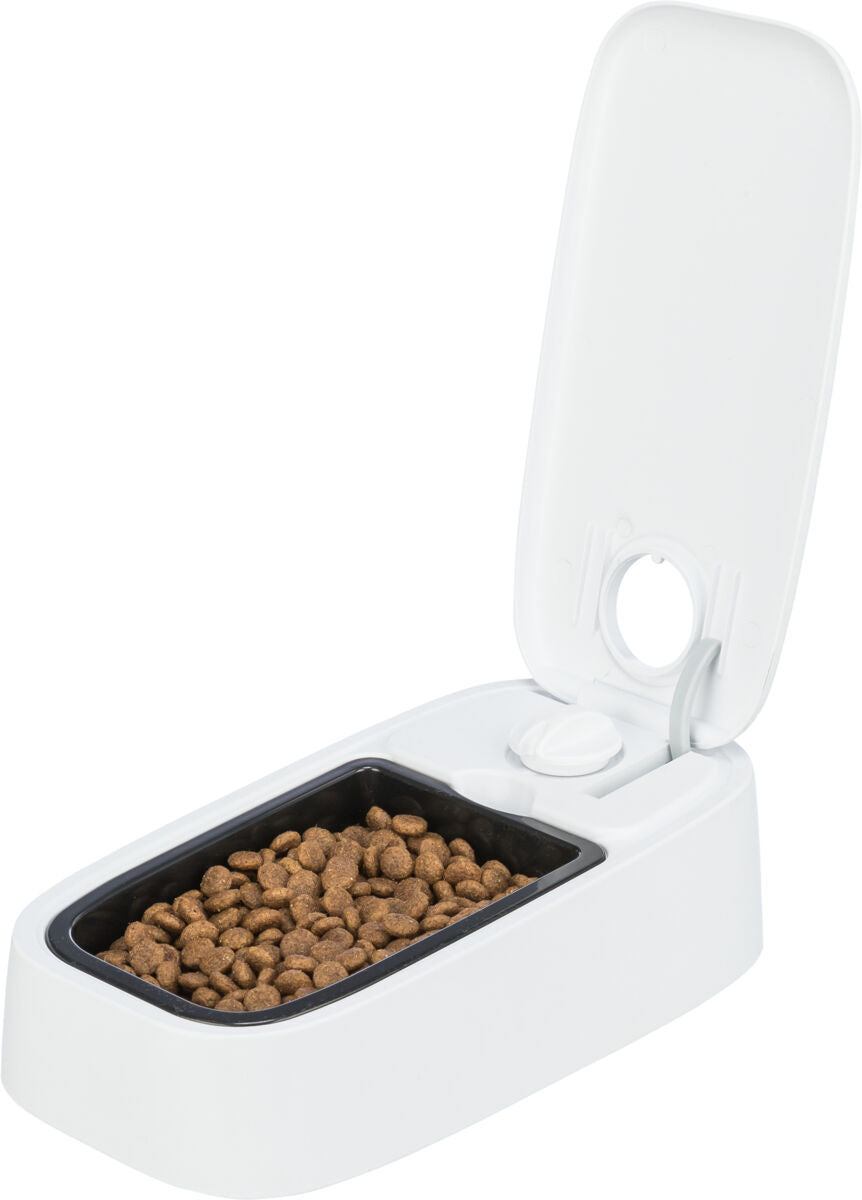 Automatischer Tierfutternapf mit geöffnetem Deckel und braunen Kroketten in einem schwarzen Fach.