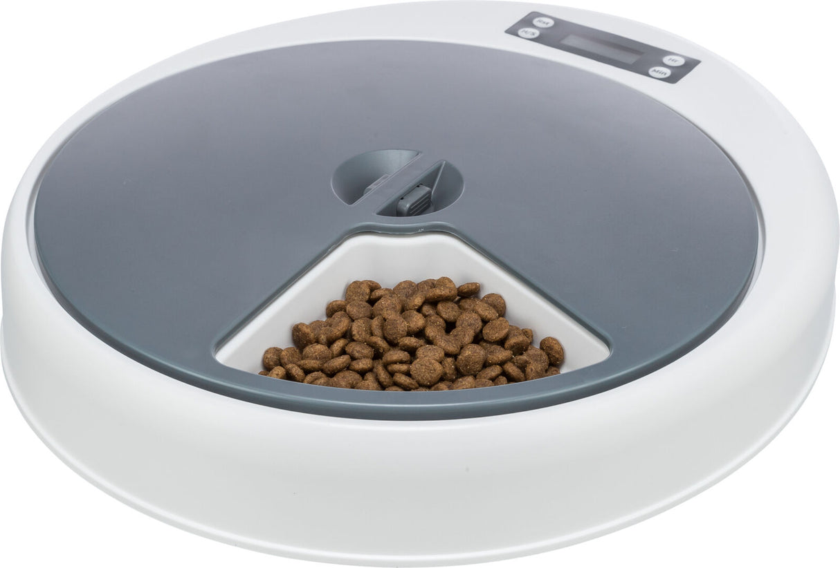 Runder Futterspender mit grauer Abdeckung und digitalem Display, gefüllt mit braunen Trockenfutterstücken.