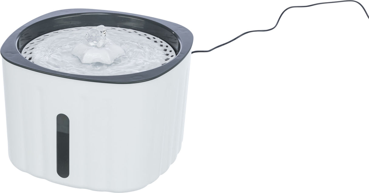 Weißer, runder Trinkbrunnen mit schwarzem Rand und sprudelndem Wasser, Kabel an der Seite.