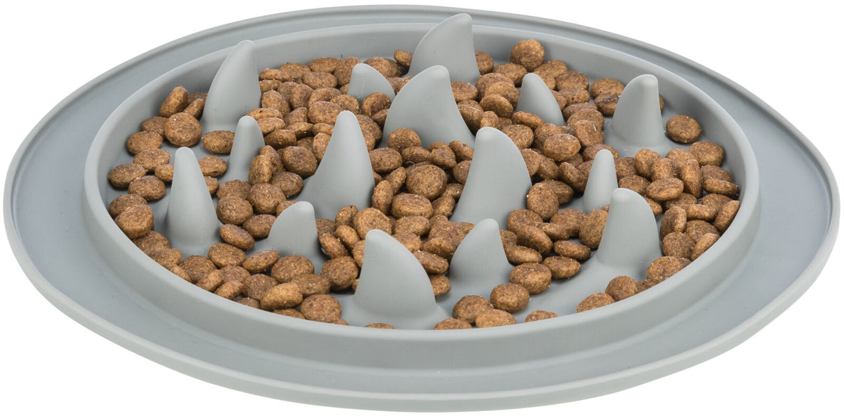 Grauer Futternapf mit Erhebungen gefüllt mit braunem Trockenfutter, das unregelmäßig verteilt ist.