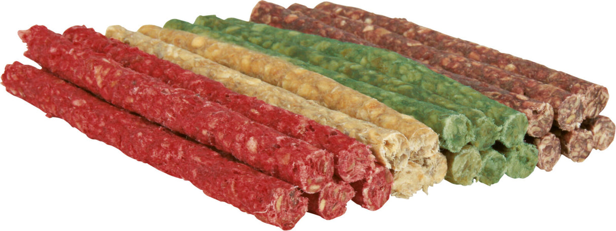 Bunte Hundesnacks in Grün, Rot, Gelb und Braun liegen gestapelt auf einer hellen Oberfläche.