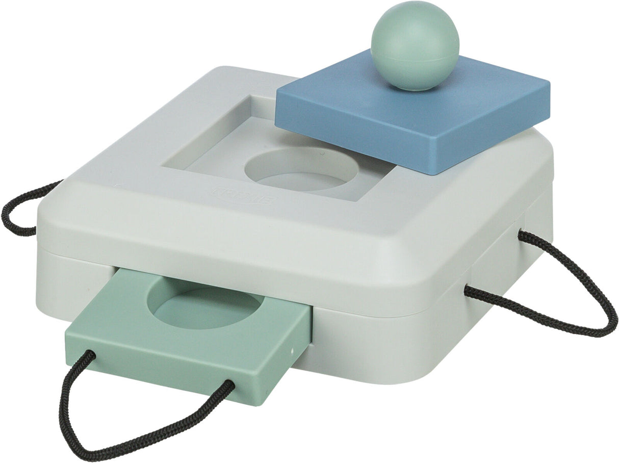 Quadratische weiße Box mit blauen und grünen Elementen, runder Ball oben, zwei herausziehbare, gelochte Platten an den Seiten.