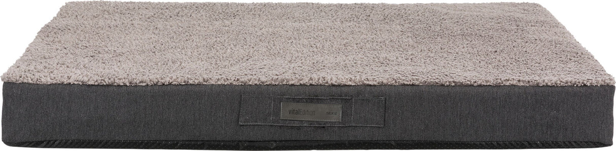 Rechteckiges graues Hundebett mit weicher Oberfläche, Label "vitalEdition Trixie" sichtbar auf der Seite.