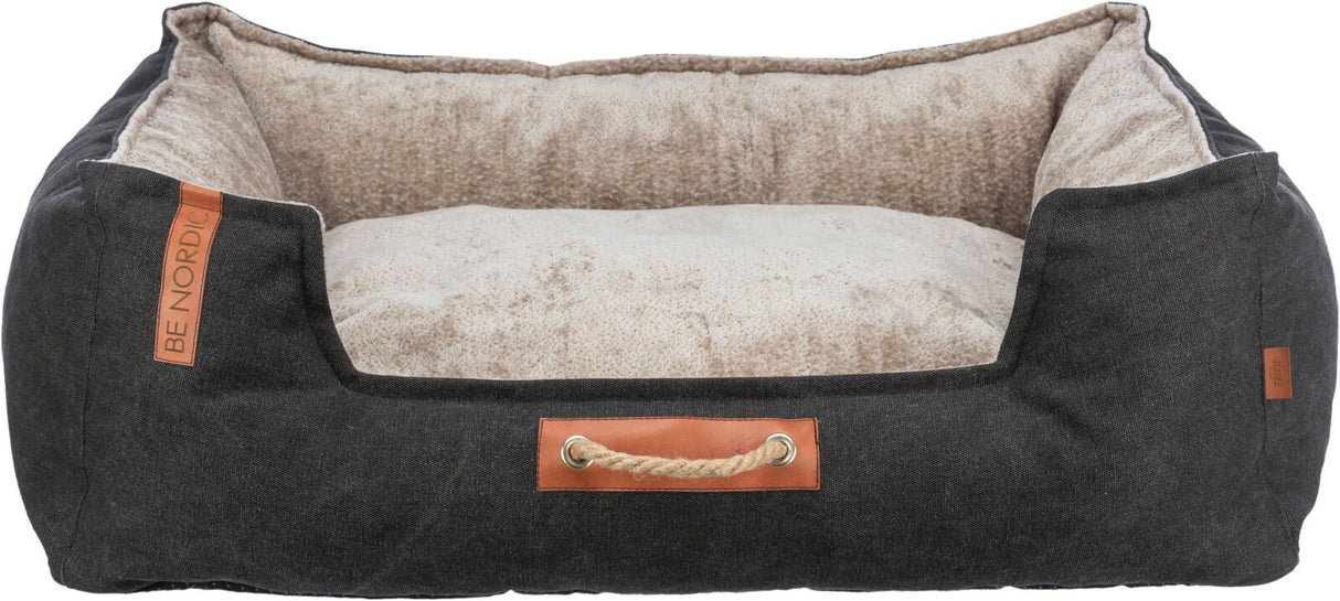 Hundebett mit dunkelgrauem Stoffbezug und heller, weicher Innenseite, vorne mit braunem Lederdetail und Seilgriff.