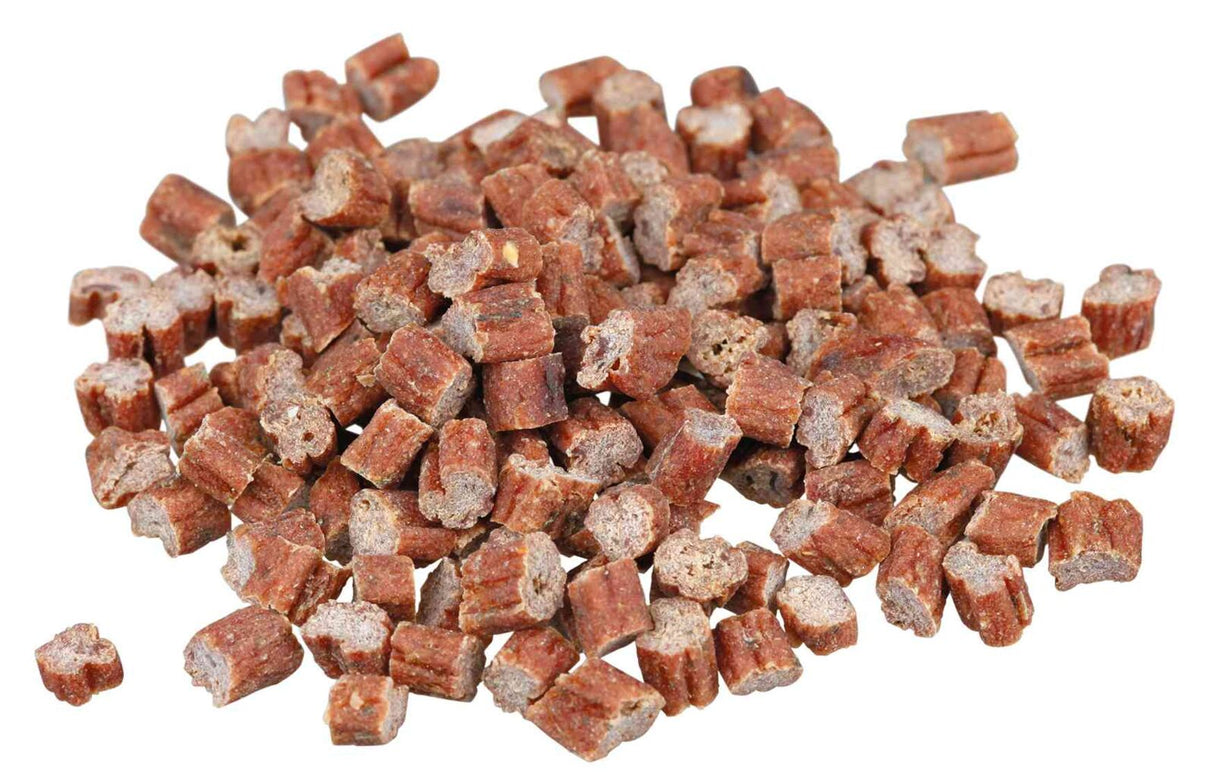 Eine Häufung von braunen, zylinderförmigen Hundesnacks auf einer weißen Oberfläche.