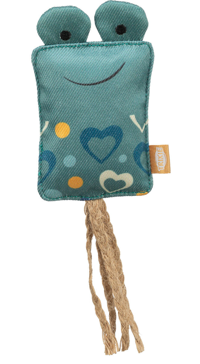 Grünes Stoffspielzeug mit zwei Augen, Herz- und Punktmustern, zwei beige Kordeln hängen unten herunter.