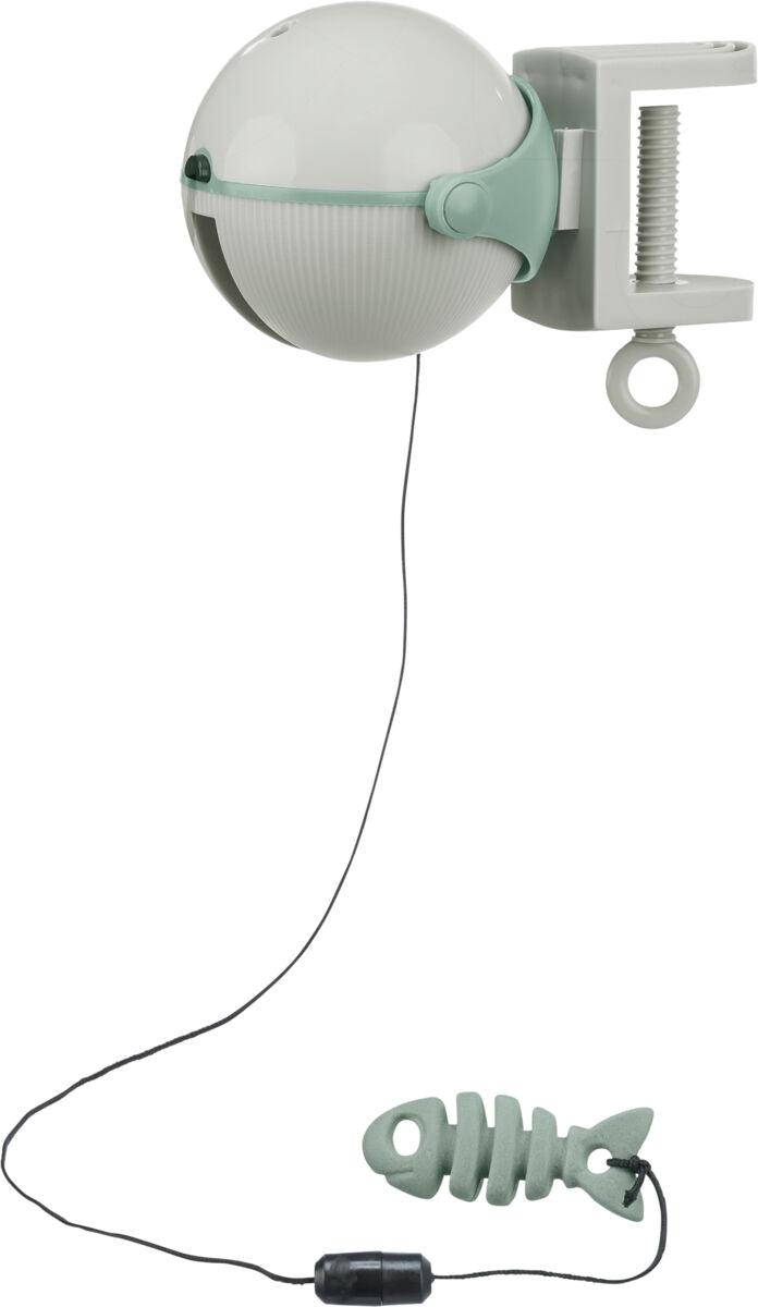 Runde, weiße Vorrichtung mit grüner Klemme und Schnur, am Ende ein grünes Fischspielzeug, an der Wand befestigbar.