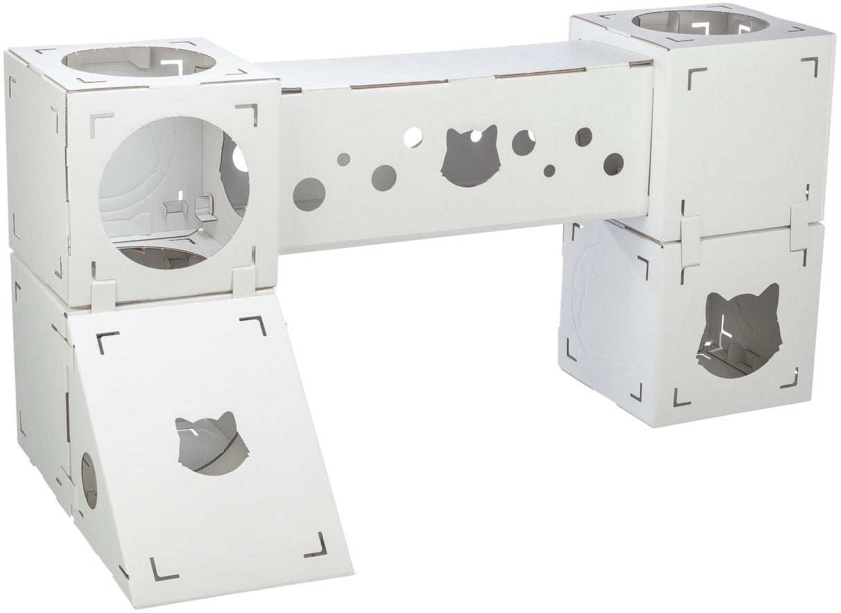 Weiße modulare Kartonstruktur mit Würfeln und Röhren, Öffnungen in Katzenform und runde Löcher sichtbar.