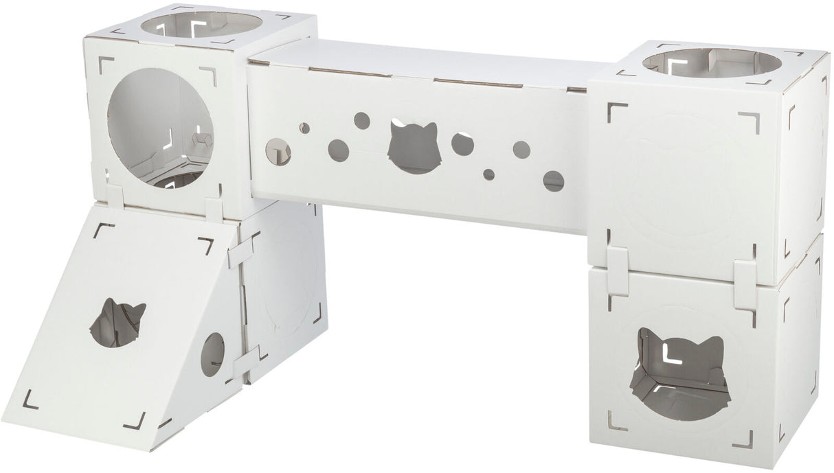 Weiße modulare Struktur mit Würfeln und Röhren, einige mit katzenförmigen Öffnungen und runden Löchern.