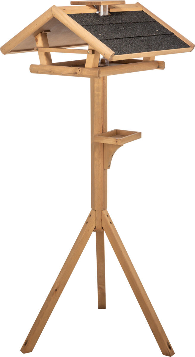 Holzfarbenes Vogelhaus auf einem dreibeinigen Ständer mit grauem Dach aus grobem Material.