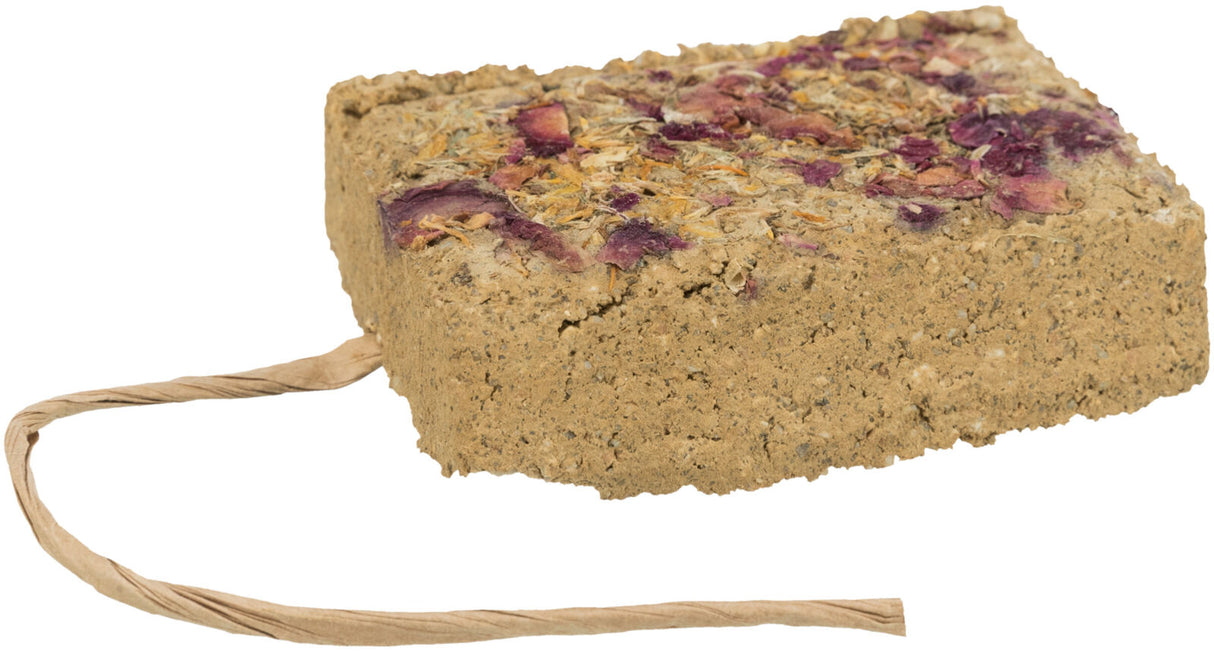 Ein rechteckiger Block aus bräunlichem Material mit getrockneten Blüten und einer Schnur an einer Ecke.