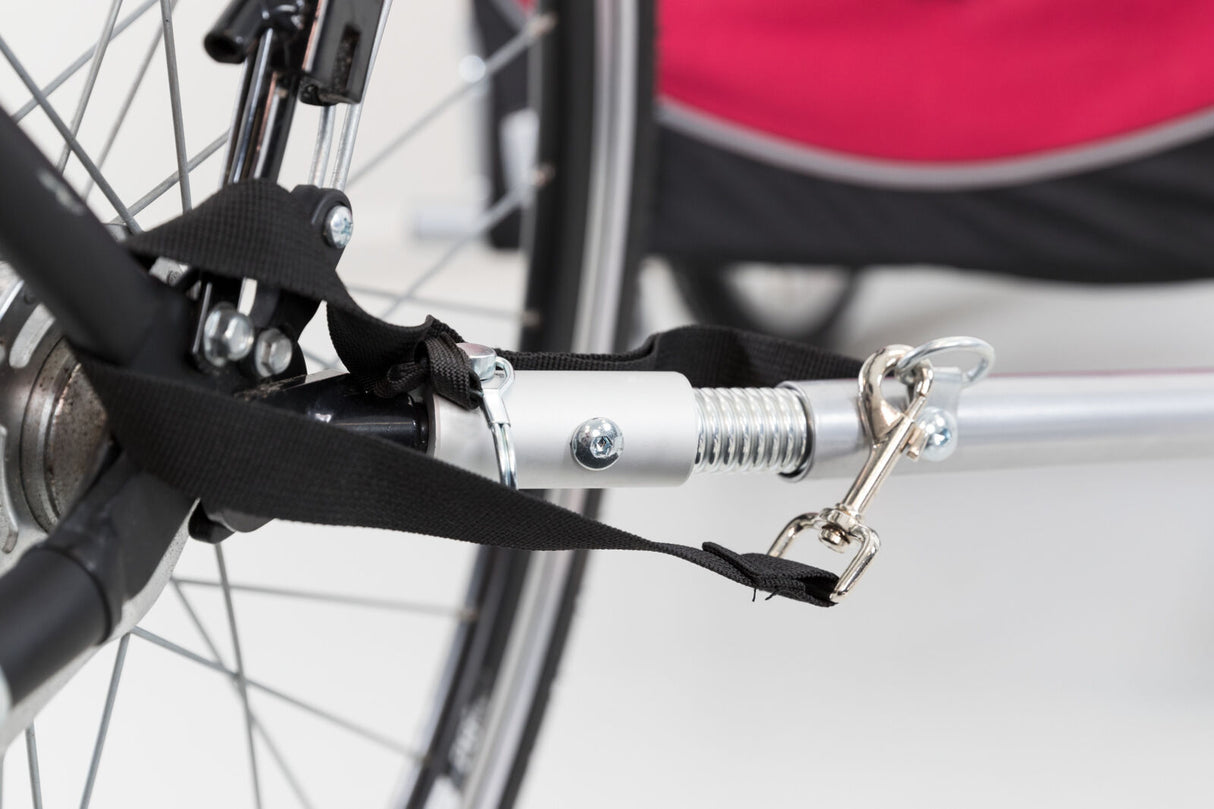 Nahaufnahme einer Anhängerkupplung aus Metall mit schwarzen Gurten, befestigt an einem Fahrradrahmen.