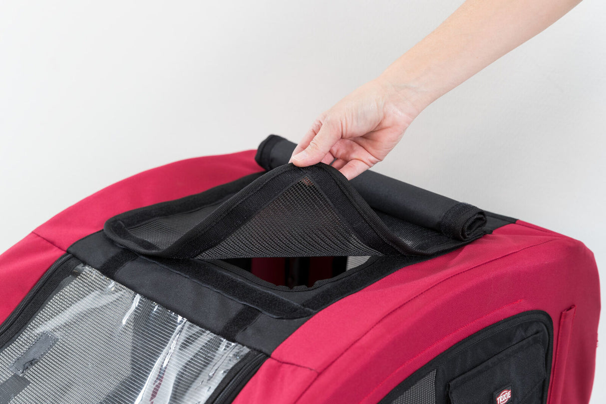 Person hält das Netz des roten Fahrradanhängers mit schwarzer Umrandung hoch.