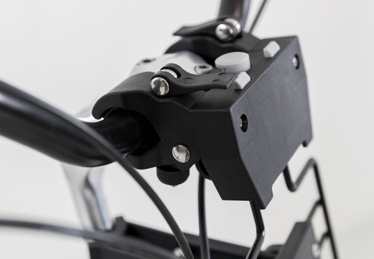 Schwarzer Fahrradlenker mit Befestigungselementen und Kabelhaltern; Hintergrund unscharf und hell.