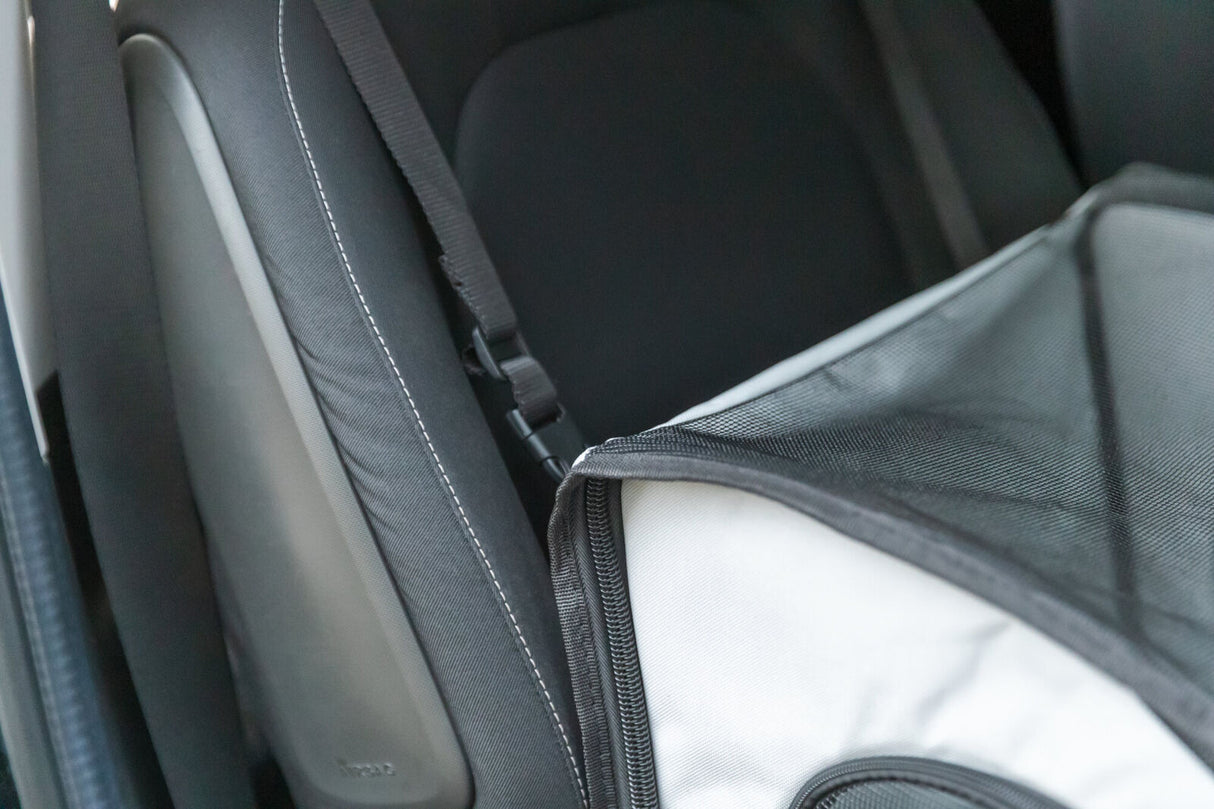 Schwarzer Autogurt mit schwarzem Netz an grauem Sitz befestigt.