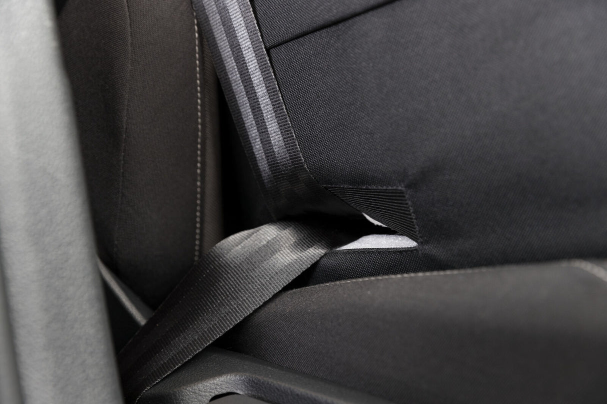 Schwarzes Sitzmaterial mit grauem Sicherheitsgurt und weißen Nähten in Nahaufnahme sichtbar.