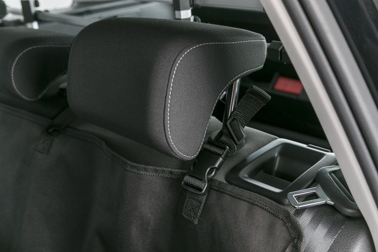 Schwarze Kopfstütze und Sicherheitsgurt auf einem Autositz mit grauer Naht und schwarzem Verstellgurt.