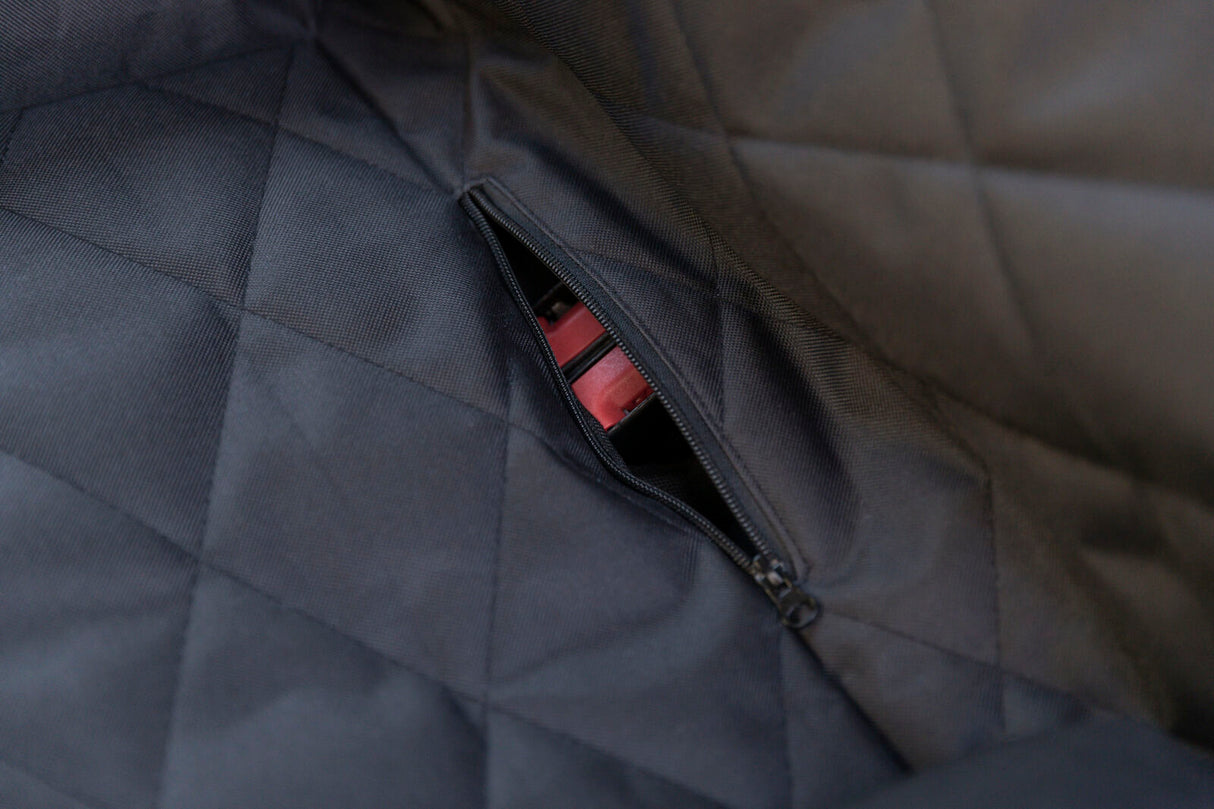 Ein schwarzer gepolsterter Stoff mit einem leicht geöffneten Reißverschluss, der rote Gegenstände zeigt.