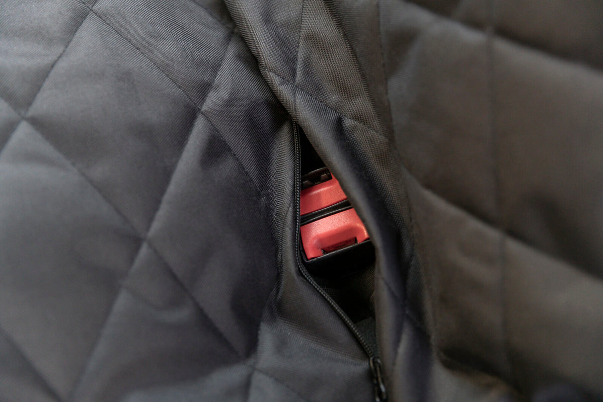 Nahaufnahme eines schwarzen gesteppten Stoffes mit einem sichtbaren roten Autogurt durch einen Reißverschluss.