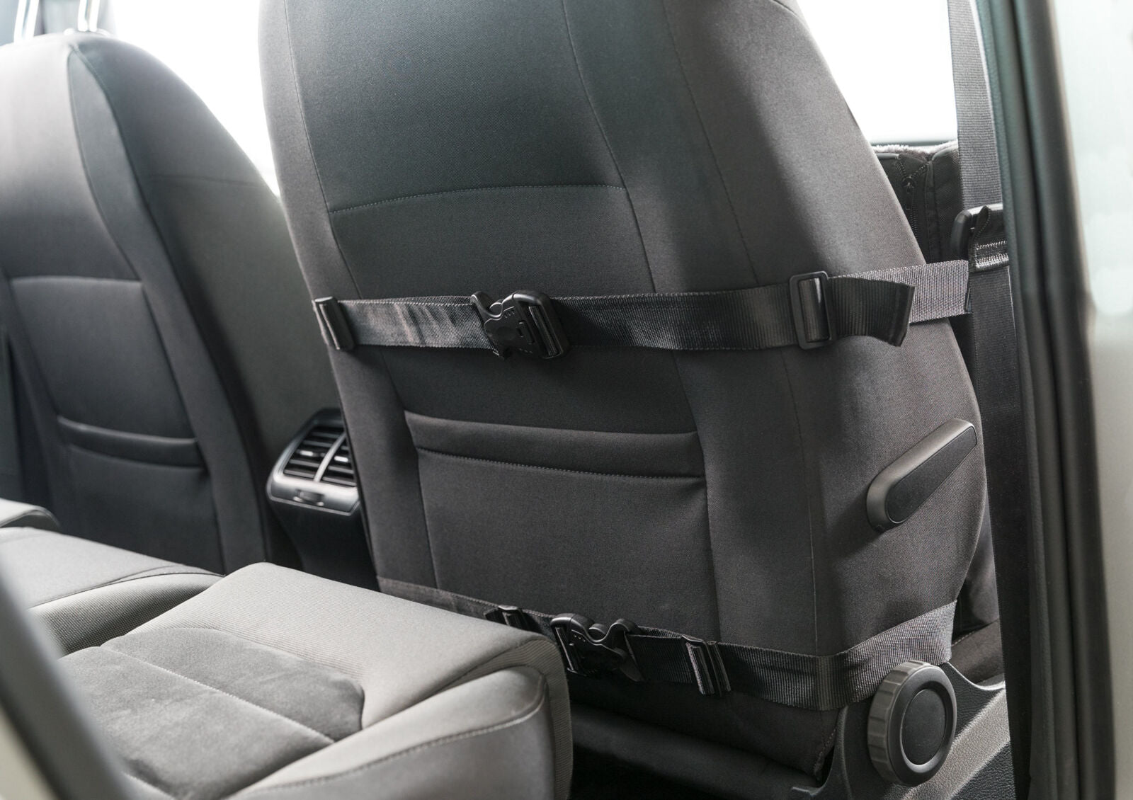 Rückseite eines Autositzes mit schwarzen Stoffbezügen und Befestigungsgurten.