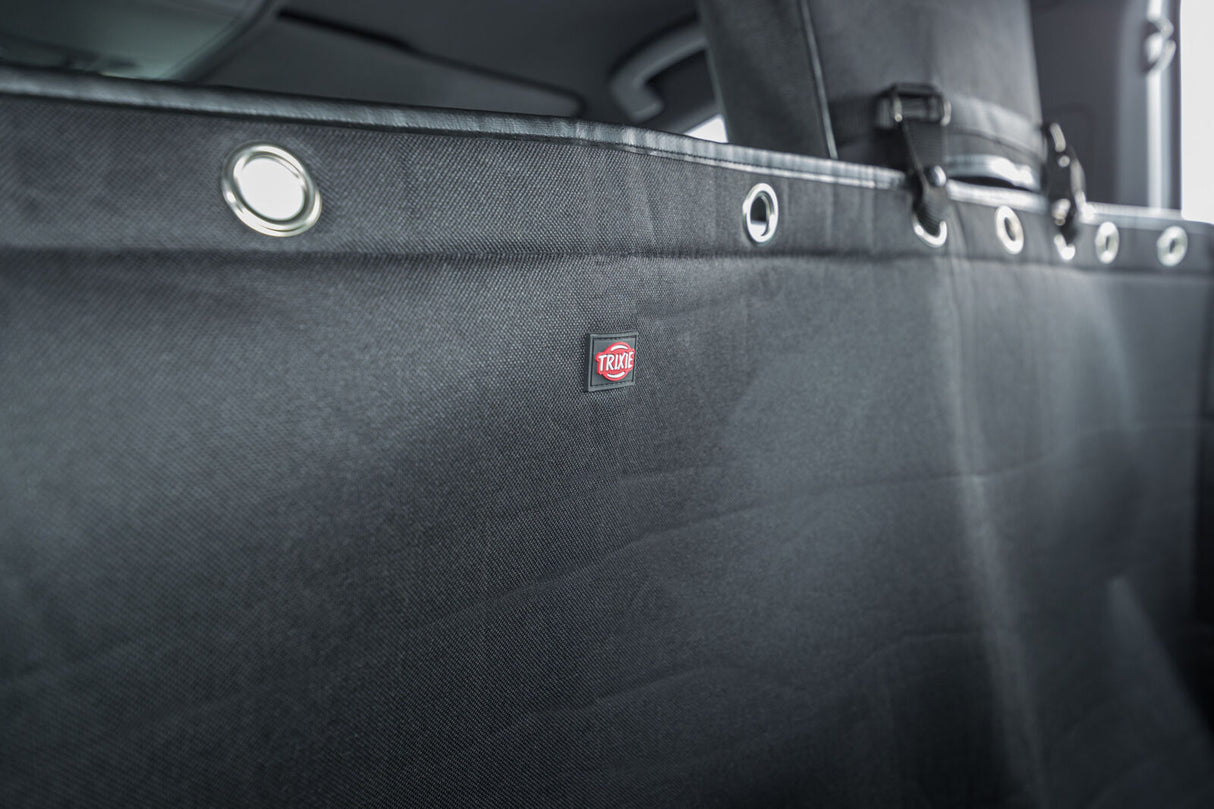 Schwarzer Autositzschutz mit verstärkten Metallösen und einem Trixie-Logo in einem Fahrzeug.