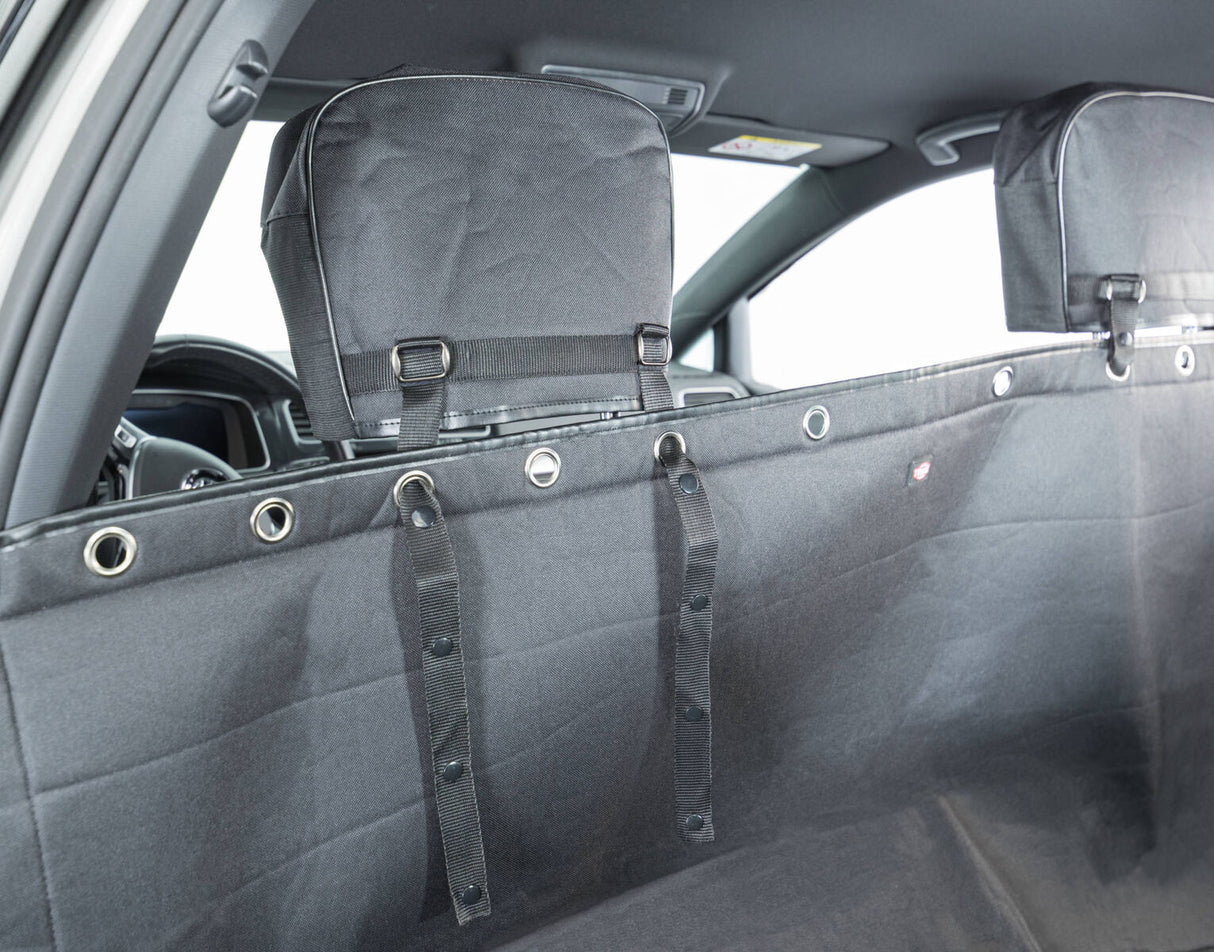 Schwarzer Schutzbezug im Auto mit mehreren Ösen und Gurten, innenansicht vor Rücksitzbereich.