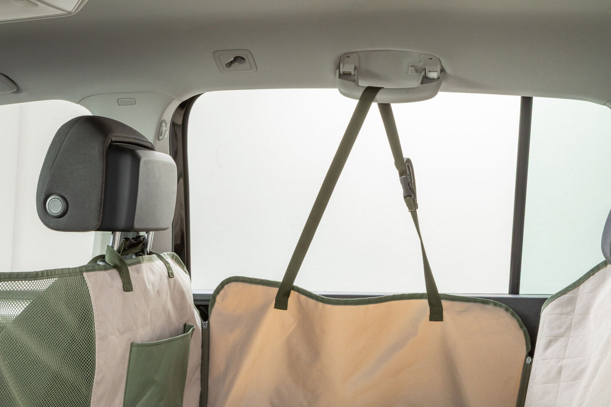 Beige und grüner Rücksitzschoner mit Gurtsystem in einem Auto befestigt.
