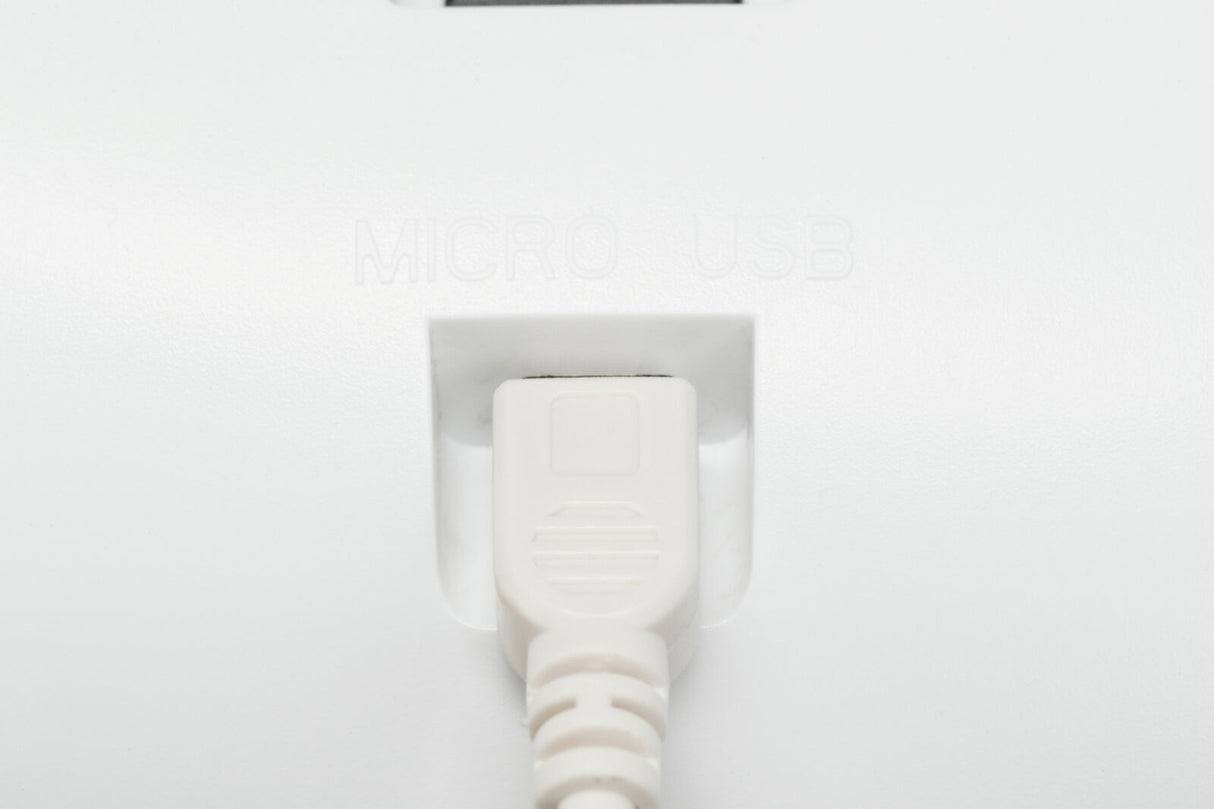 Ein weißes Mikro-USB-Kabel ist in einer entsprechenden Buchse eingesteckt, darüber der Text "MICRO USB".