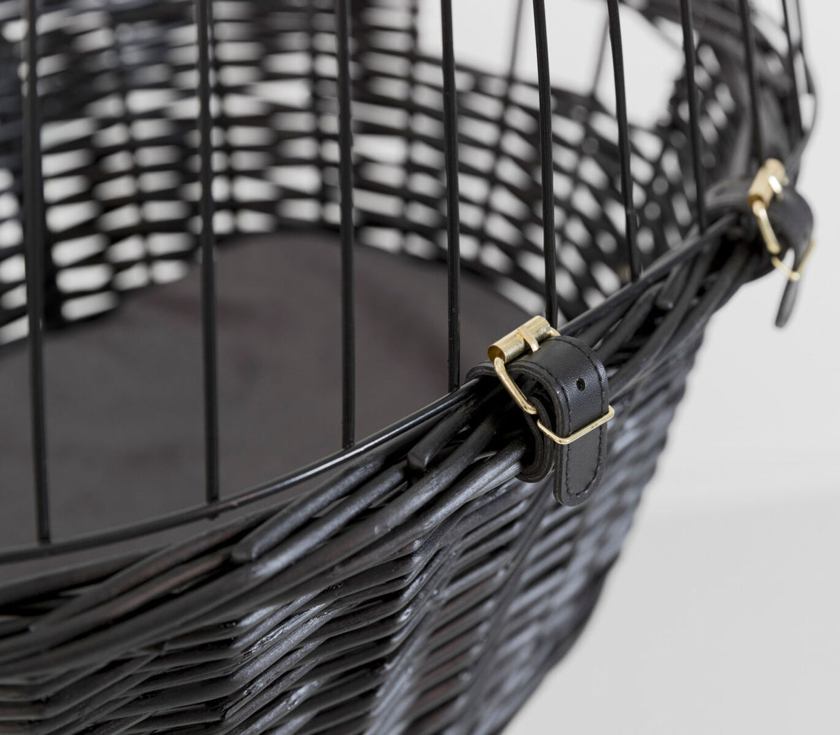 Nahaufnahme eines schwarzen, geflochtenen Korbs mit Metallstäben und goldfarbenen Schnallen.