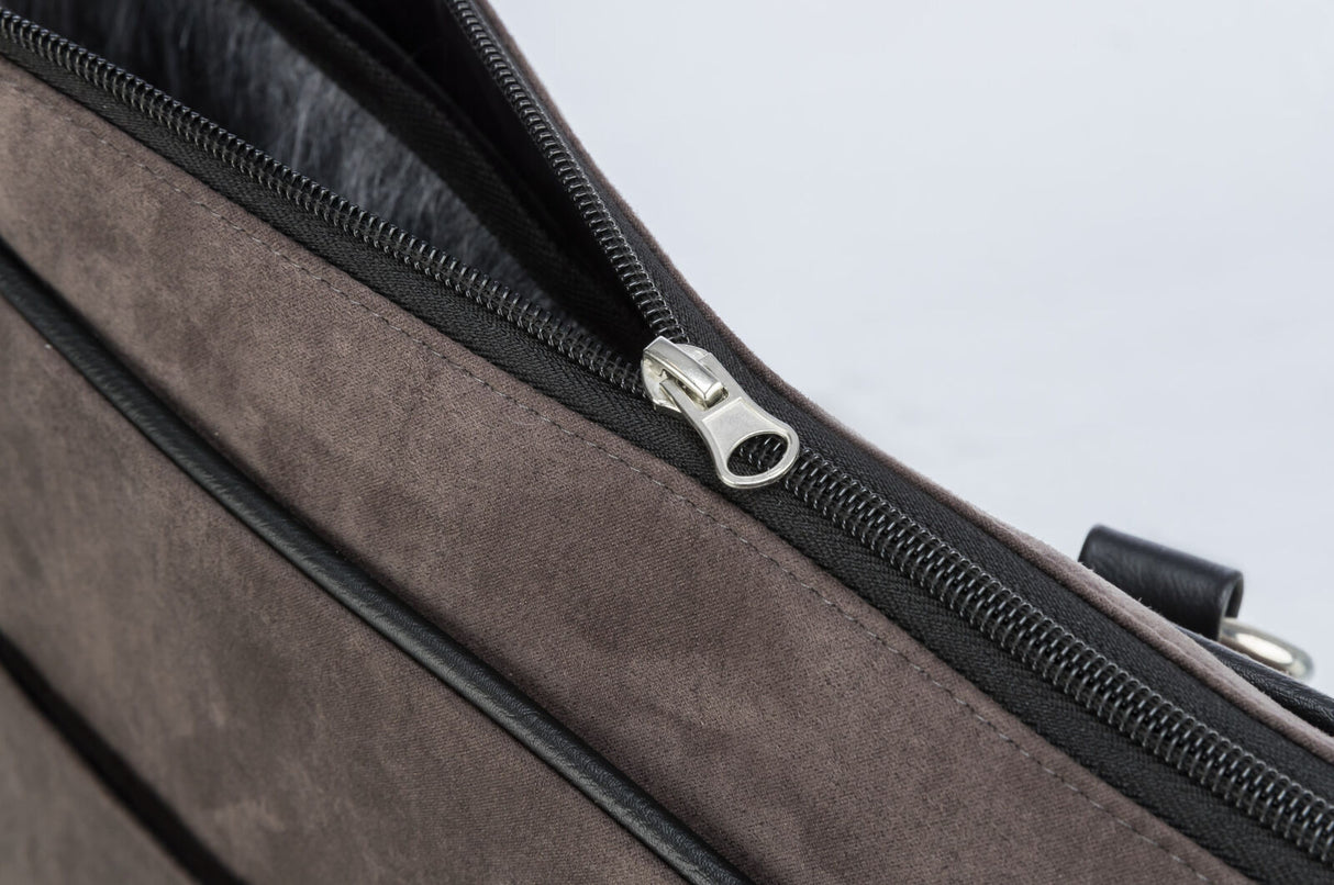 Nahaufnahme eines grauen Stoffmaterials mit einem schwarzen Reißverschluss und einem silbernen Schiebergriff.