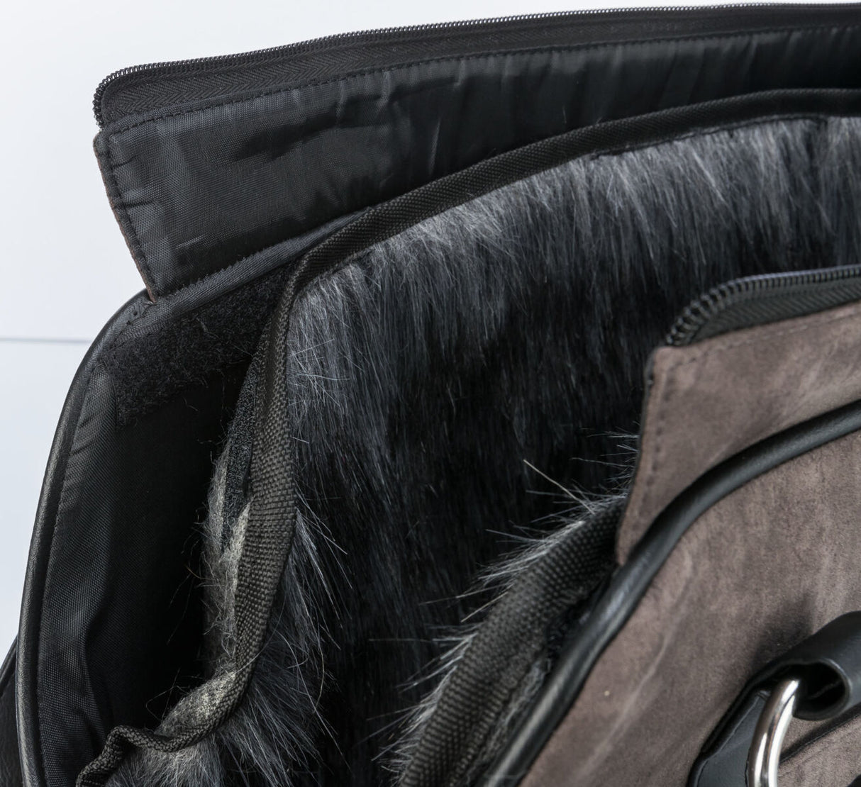 Detailaufnahme einer schwarzen Tasche mit Fellbesatz und Reißverschluss.